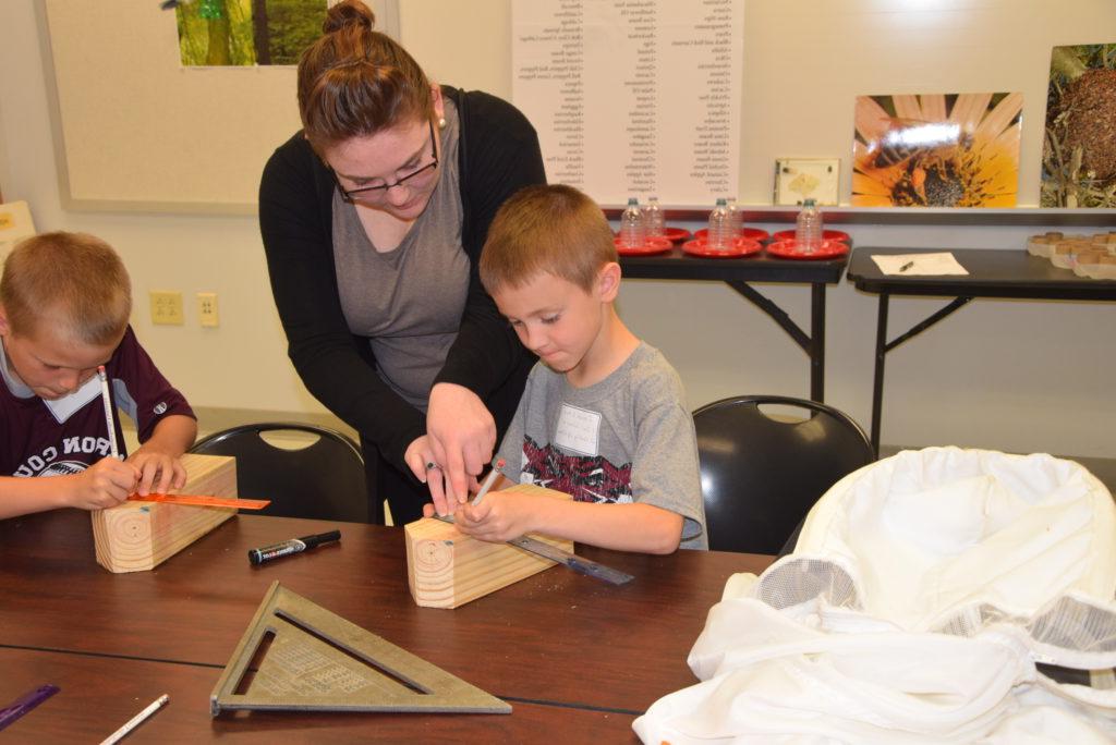 Jordan Greer, center, served as an assistant during the Kids College Cool Science class on Campbellsville University's campus. Greer assisted students, from left, Isaiah Litton of Campbellsville, Ky. and Oaks Mattingly of Lebanon, Ky. with the measurements for their home-made bee hives. (Campbellsville University Photo by Ariel Emberton)